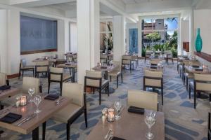 科默斯洛杉机希尔顿逸林酒店的餐厅设有木桌、椅子和窗户。