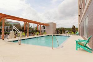 奥兰多Home2 Suites By Hilton Orlando South Park的一座带绿椅的游泳池,位于一座建筑旁边