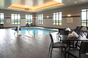 匹兹堡Hampton Inn & Suites Pittsburg Kansas Crossing的酒店大堂设有一座带桌椅的游泳池