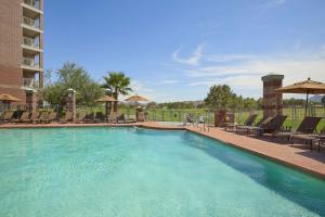 凤凰城Embassy Suites by Hilton Phoenix Scottsdale的度假村的游泳池,配有椅子和遮阳伞