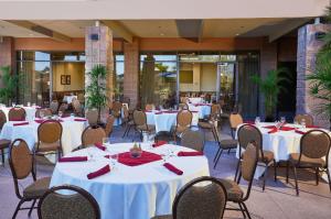 凤凰城Embassy Suites by Hilton Phoenix Scottsdale的一间设有白色桌椅的用餐室