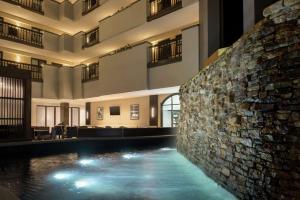 阿尔法利塔希尔顿亚特兰大阿尔法利塔使馆套房酒店的一座石头墙建筑中间的游泳池