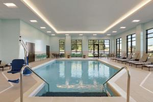 奥尔巴尼Homewood Suites by Hilton Albany Crossgates Mall的大楼内带桌椅的大型游泳池