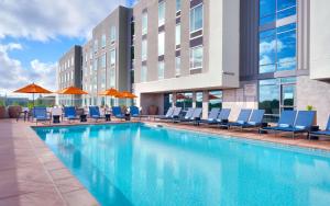 安纳海姆Hampton Inn & Suites Anaheim Resort Convention Center的游泳池,酒店配有椅子和遮阳伞