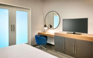安纳海姆Hampton Inn & Suites Anaheim Resort Convention Center的一间卧室配有一张桌子、一台电视和一面镜子