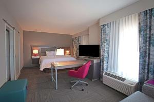 阿什维尔Hampton Inn & Suites Asheville Biltmore Area的酒店客房配有一张床、一张书桌和一台电视。