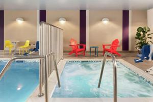 俾斯麦Home2 Suites By Hilton Bismarck的游泳池位于酒店客房内,配有椅子和桌子