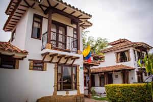 莱瓦镇El Pozzo Hotel Campestre的带阳台和旗帜的白色房屋