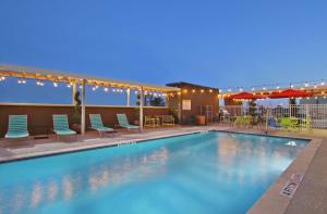 亚瑟港Home2 Suites By Hilton Port Arthur的夜间游泳池,配有椅子和遮阳伞