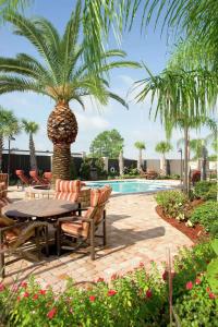 巴吞鲁日10号州际公路&学院大道恒庭酒店的一个带桌椅和棕榈树的庭院