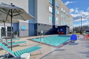 巴吞鲁日Tru By Hilton Baton Rouge Citiplace的一座带椅子和遮阳伞的游泳池位于大楼旁