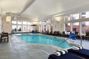 伯灵顿伯灵顿希尔顿惠庭套房酒店的一座带椅子和桌子的酒店游泳池