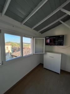 Ozzano MonferratoLa Casetta di Treville的白色的客房设有大窗户和电视。