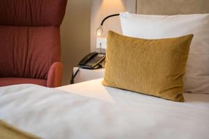 茨维考茨维考第一酒店的一张带黄色枕头的床和一部电话