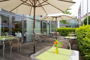 弗赖辛ACHAT Hotel Corbin München Airport的一个带桌椅和遮阳伞的户外庭院。