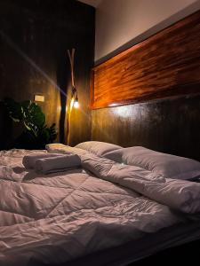 卢纳将军城M-Resort Siargao的一张配有白色床单和木制床头板的大床