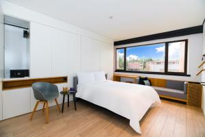 北京Stey公寓（北京工体三里屯店）的卧室配有一张白色大床和一把椅子