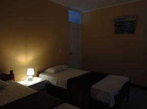 皮斯科Hostal Madrid的一间卧室设有两张床和一张桌子上的台灯。