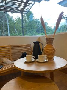 TapokrengVogelkopf Resort的一张桌子,上面有两个咖啡杯和花瓶