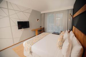 达累斯萨拉姆Giraffe Beach Hotel的卧室配有白色的床和电视。