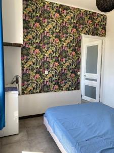 勒卡内Appartement PALOMA Proche Cannes的一间卧室配有蓝色的床和花卉壁纸