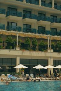 锡德Castival Hotel的游泳池里设有椅子和遮阳伞的酒店