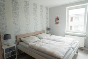 格洛米茨Appartementhaus Christel的一间卧室配有一张带白色床单的床和一扇窗户。