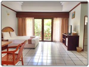 Prasat通皮克酒店的一间卧室配有一张床、一张桌子和一台电视
