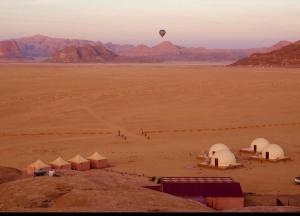 瓦迪拉姆Aljawhara camp and activities的热气球在沙漠上空,有帐篷
