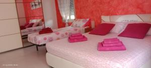伦蒂尼Rubino house的客房内的两张床和粉红色的毛巾