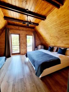 苏恰瓦Twin Cabins / Cabanele Gemene的一间卧室设有一张大床和木墙