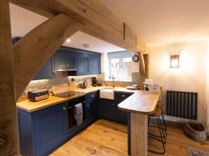 BledingtonCotswold cottage with hot tub的厨房铺有木地板,配有蓝色橱柜。