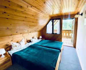 鲁恰内尼达Zielony Domek的木制客房内的一间卧室配有两张床