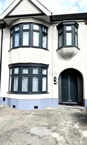 伍德福德格林4 Bed Family Home的白色的房子,有黑窗和车道