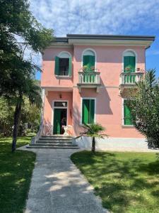 威尼斯丽都Venezia Lido Villa Delle Palme的粉红色的房子,设有绿色百叶窗和走道