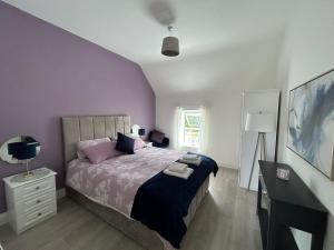 斯尼姆Sneem Studios的一间卧室配有一张紫色墙壁的床和一张书桌