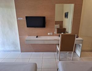 岩望Makati Pasuruan Hotel的一间房间,配有一张桌子和一台墙上的电视