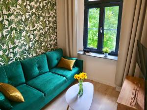 格利维采Loft Apartments Gliwice的客厅配有绿色沙发和桌子