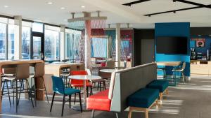 比林斯avid hotels Billings West, an IHG Hotel的餐厅设有多彩的桌椅和窗户。