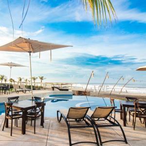 阿卡普尔科Mishol Bodas Hotel & Beach Club Privado的海滩旁带桌椅的游泳池
