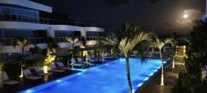 帕纳米林Dunas de Cotovelo的夜间酒店游泳池,带椅子和棕榈树