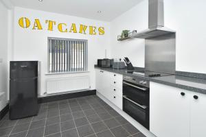 特伦特河畔斯托克Potter's Rest by YourStays的厨房配有白色橱柜和黑色冰箱。