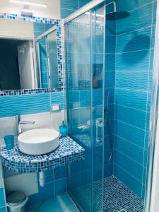 伊斯基亚Apartaments B&M的蓝色瓷砖浴室设有水槽和淋浴