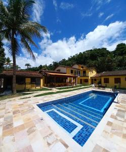 帕拉蒂Pousada Antígona的棕榈树屋前的游泳池