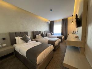 安曼Kaya Hotel Amman的酒店客房设有两张床和电视。
