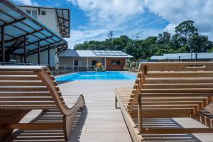 MacouriaHôtel Belle Terre Resort的一座游泳池,旁边设有两个木凳