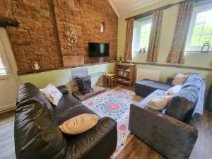 Great SalkeldGarth at Wetheral Cottages的客厅配有皮革家具和砖墙