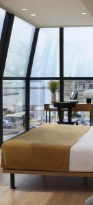 塞萨洛尼基Noa Hotel的卧室配有床和书桌,房间设有窗户