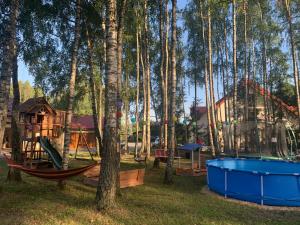 CisówPensjonat Leśny Dworek SPA & Garden Uzdrowisko wśród Natury的一个带秋千的游乐场和树林中的房屋