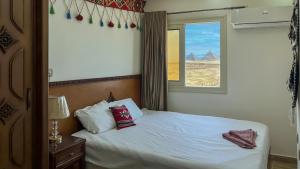 GizaAtlantis Pyramids Inn New的一间卧室设有一张床和一个享有山景的窗户。